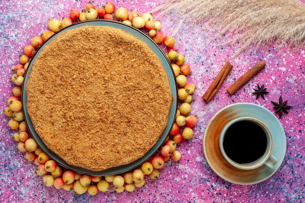 Top view delicious round cake inside plate with lined sweet cherries and tea on the bright pink desk cake pie biscuit