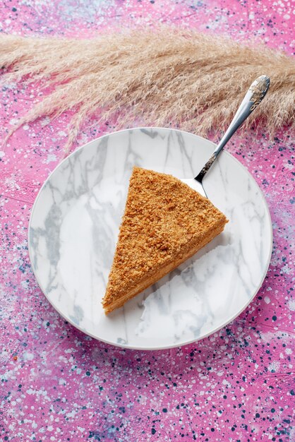 Вид сверху вкусный круглый кусочек торта внутри тарелки на ярко-розовом столе, пирог, бисквит, сладкая выпечка
