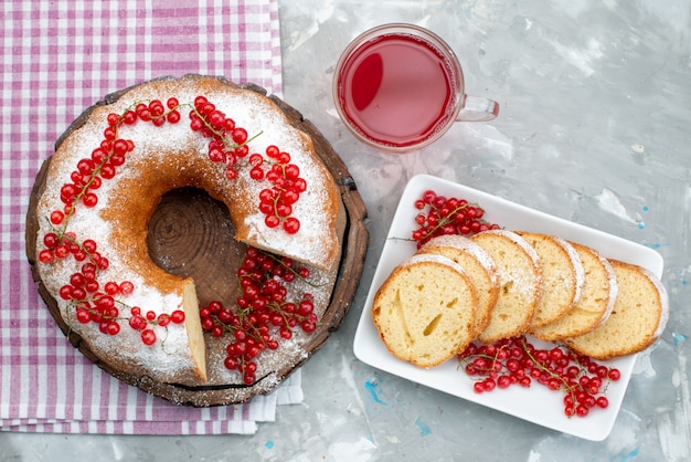 Вид сверху вкусный круглый торт со свежей красной клюквой и клюквенным соком на белом письменном столе бисквитный чай ягодный сахар