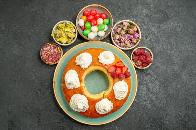 Вид сверху вкусный круглый пирог с конфетами на сером фоне печенье бисквитный торт пирог сладкий чай