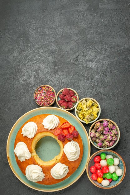 Вид сверху вкусный круглый пирог с конфетами на сером фоне сахарное печенье бисквитный пирог сладкий чай