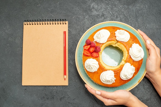 Top view delicious round pie with fruits and cream on dark background tea sugar cookies biscuit cake sweet