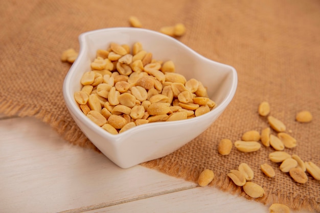 Top view of delicious salty pine nuts on a bowl on a sack cloth on a beige wooden table