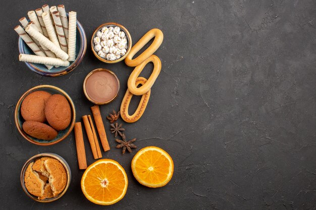 Вид сверху вкусное песочное печенье со свежими апельсинами на темном фоне, печенье, сахар, фрукты, сладкое цитрусовое печенье