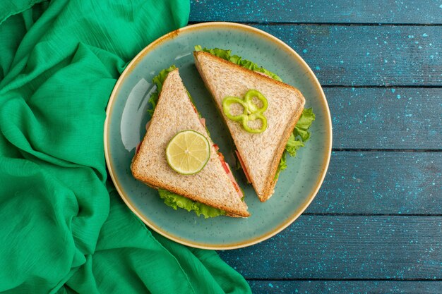 top view of delicious sandwiches inside blue plate on the blue desk