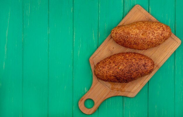 Top view of delicious and sesame patties on a wooden kitchen board on a green wooden background with copy space