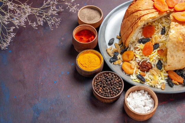 Top view of delicious shakh plov with raisins and seasonings on a dark surface