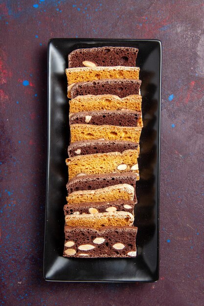 Top view delicious sliced cake with nuts inside cake pan on dark background sweet cocoa cake biscuit pie sugar cookies