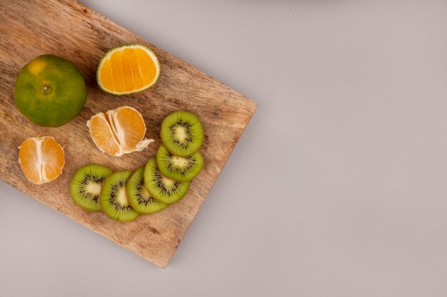 Top view of delicious sliced kiwi with tangerines on a wooden kitchen board with copy space