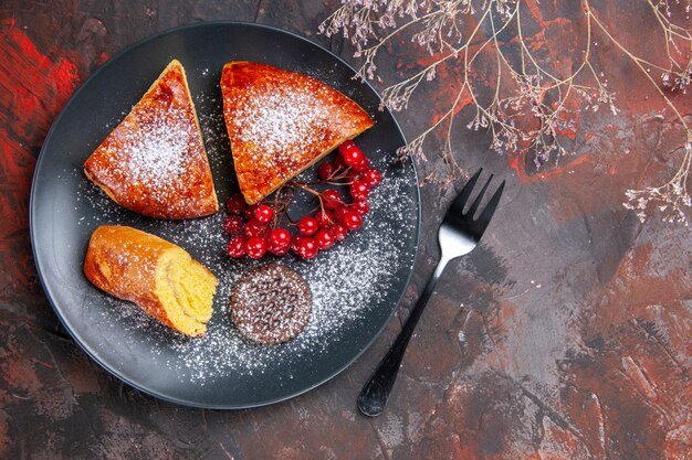 Top view delicious sliced pie with red berries on dark table cake sweet pie