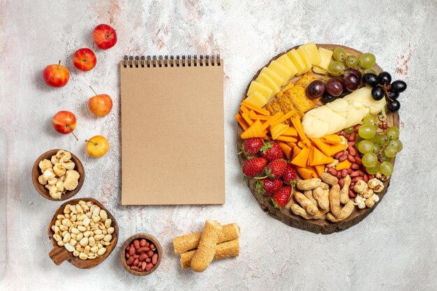 Foto gratuita vista dall'alto di deliziosi snack cips uva formaggio e noci sulla superficie bianca