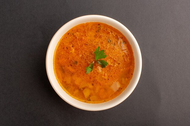 Top view of delicious soup inside plate on dark surface