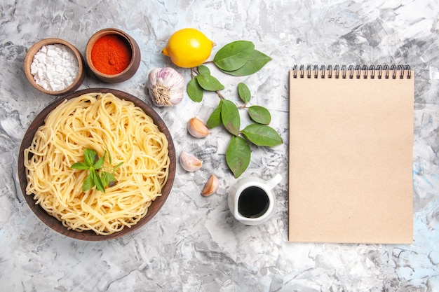 Top view delicious spaghetti with seasonings on white floor dinner pasta dough meal