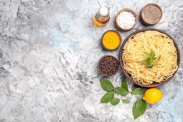 Top view delicious spaghetti with seasonings on a white floor meal dough dish pasta