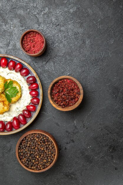 Top view of delicious squash meal with fresh red dogwoods and seasonings on dark grey surface