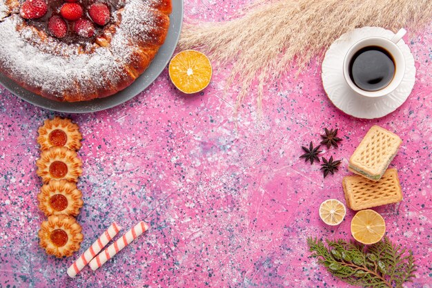 Top view delicious strawberry cake sugar powdered cake with cookies waffles and cup of tea on pink desk cake sweet sugar cookies pie