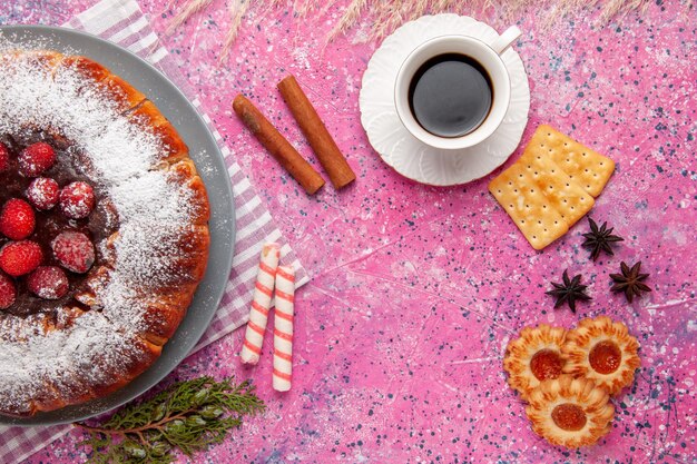 Вид сверху вкусный клубничный торт с чашкой чая крекеров и на розовой поверхности