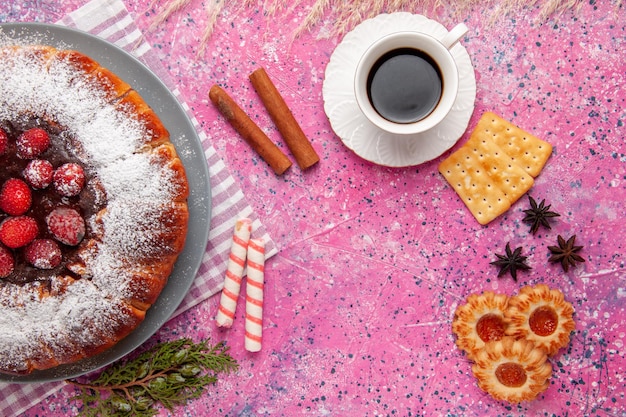 Top view delicious strawberry cake with cup of tea crackers and  on pink surface