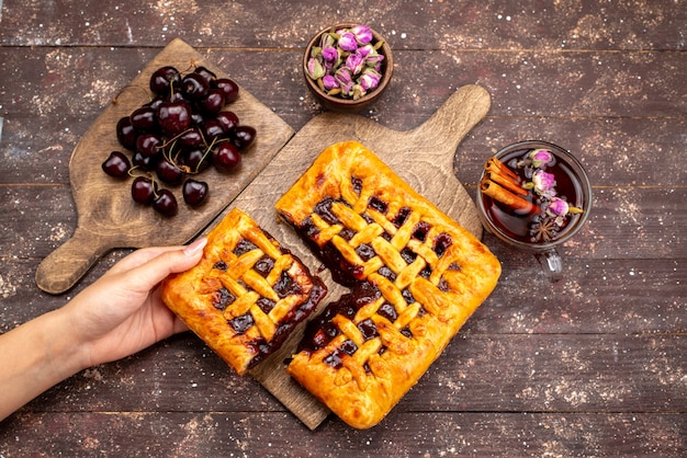 A top view delicious strawberry cake with strawberry jelly cherries and tea on the wooden desk cake biscuit sugar  berry