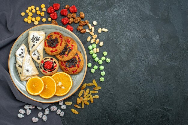 Top view delicious sugar cookies with pastries and orange slices on dark surface sugar biscuit sweet cookie tea cake