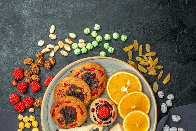 Top view delicious sugar cookies with pastries and orange slices on a dark surface sugar biscuit sweet cookies cake tea