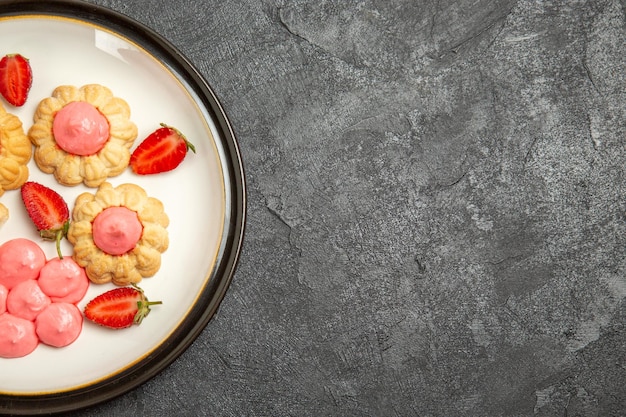 Foto gratuita vista dall'alto di deliziosi biscotti di zucchero con gelatina di fragole sulla superficie grigia