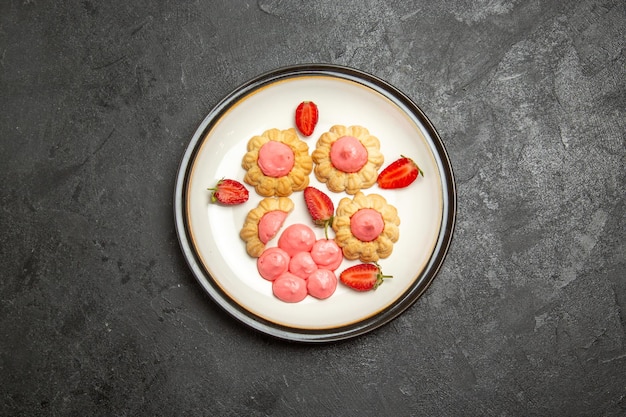 Top view of delicious sugar cookies with strawberry jelly on grey surface