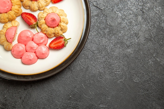 Top view of delicious sugar cookies with strawberry jelly on grey surface