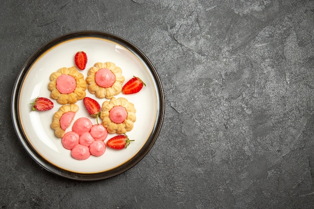 Top view of delicious sugar cookies with strawberry jelly on the grey surface