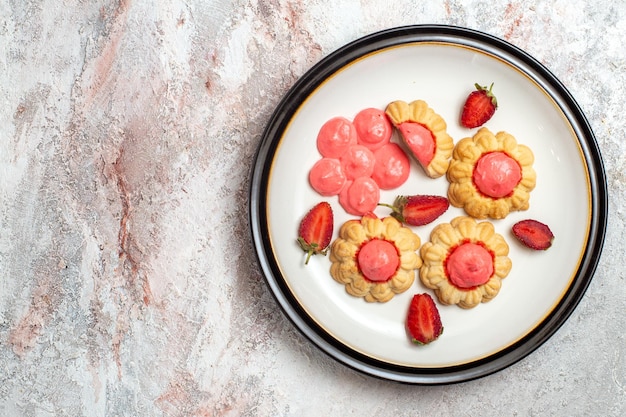 Top view of delicious sugar cookies with strawberry jelly on a white surface