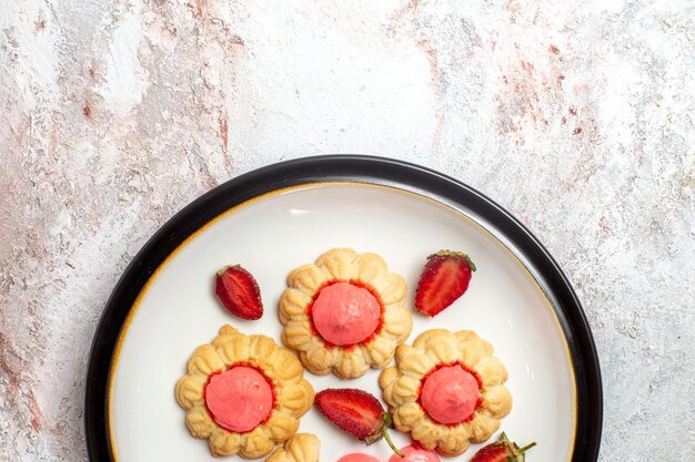 Top view of delicious sugar cookies with strawberry jelly on white surface