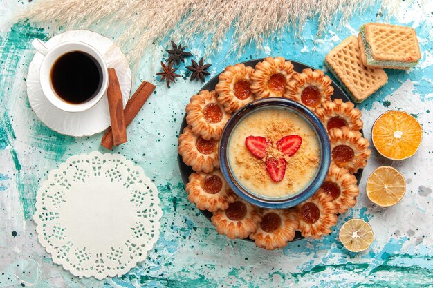 Вид сверху вкусного сахарного печенья с вафлями, чашка кофе и клубничный десерт на синем полу, печенье, печенье, сладкий торт, цвет десерта
