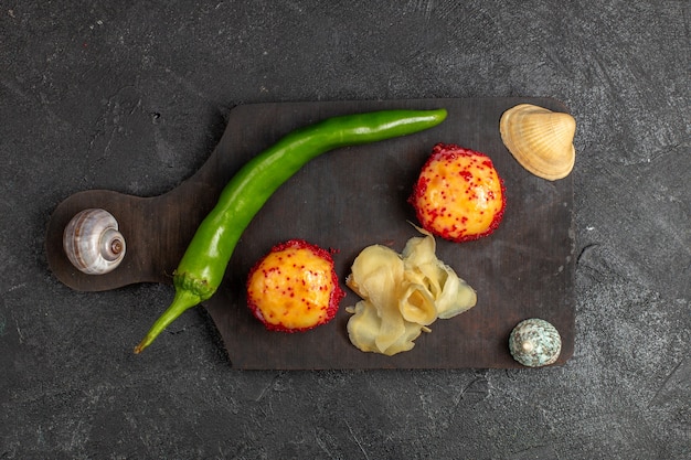 Free photo top view of delicious sushi fish rolls with fish and rice along with green pepper on grey wall