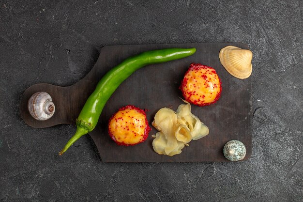 Top view of delicious sushi fish rolls with fish and rice along with green pepper on grey wall