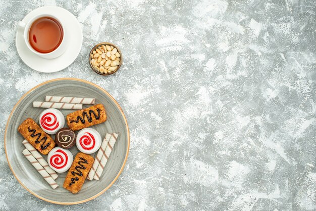 Top view delicious sweet cookies with cakes and tea on white space