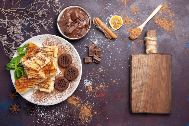Вид сверху вкусной сладкой выпечки с шоколадным печеньем на темном пространстве