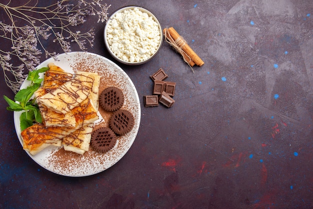 Вид сверху вкусной сладкой выпечки с шоколадным печеньем на темном пространстве