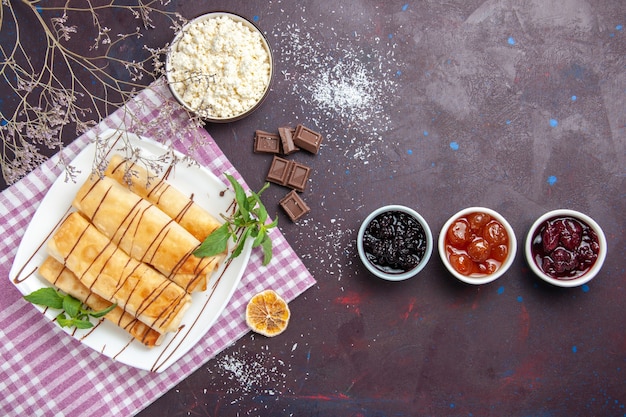 Top view delicious sweet pastries with jam and cottage cheese on dark space