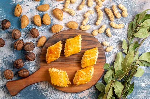 Top view of delicious sweet pastries with nuts on a blue surface