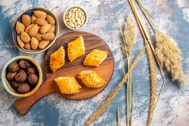 Top view of delicious sweet pastries with nuts on blue surface