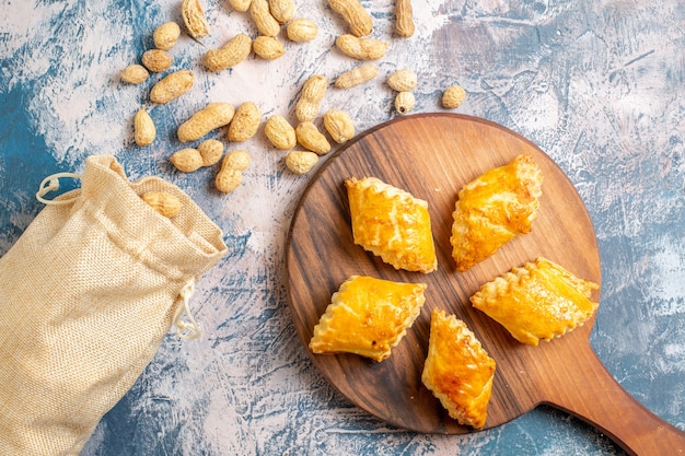 Top view of delicious sweet pastries with peanuts on blue surface