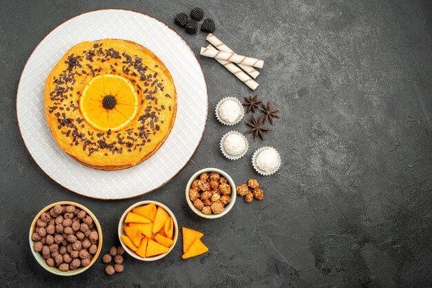 Вид сверху вкусный сладкий пирог с дольками апельсина на темно-серой поверхности фруктовый пирог из теста бисквитный