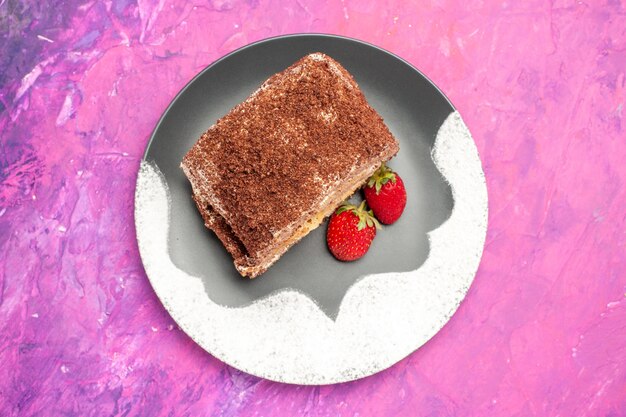 Top view of delicious sweet rolls with strawberries on pink surface