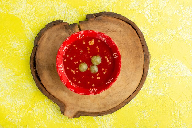 Вид сверху вкусный томатный соус с зеленым виноградом на желтом столе, суп, еда, ужин