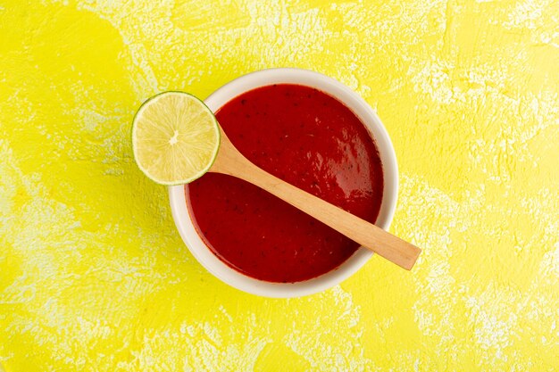 Top view delicious tomato sauce with lemon on yellow table, soup food meal dinner