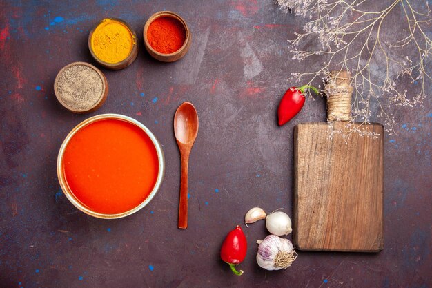 Вид сверху вкусный томатный суп, приготовленный из свежих помидоров с приправами на темном фоне томатное блюдо суп соус еда красный