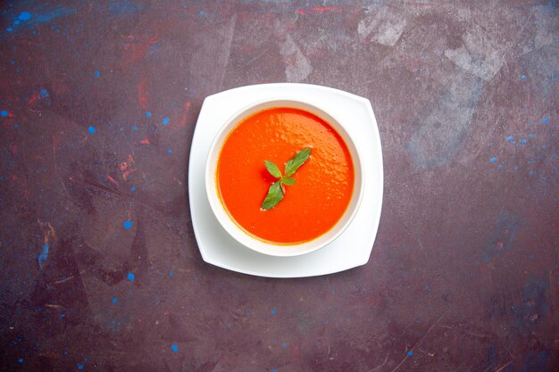 上面図おいしいトマトスープ濃い背景の皿に一枚の葉が入ったおいしい料理ソーストマト色のディナースープ