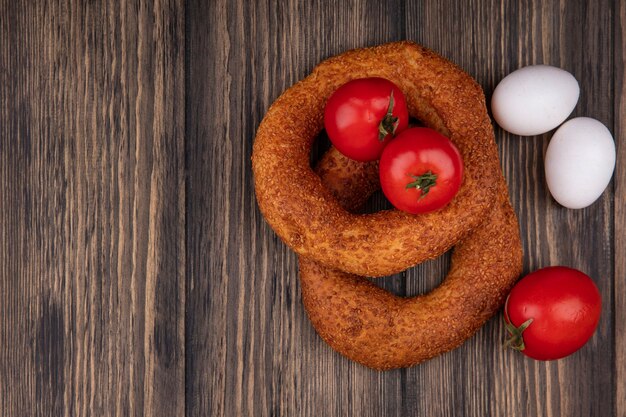 Vista dall'alto di deliziosi bagel turchi di sesamo con pomodori e uova isolate su uno sfondo di legno con spazio di copia