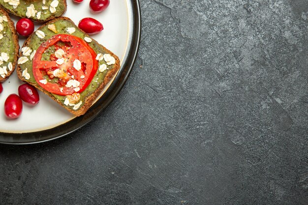 Vista dall'alto deliziosi panini utili con pasta di avocado e pomodori all'interno del piatto su sfondo grigio panino hamburger pane spuntino