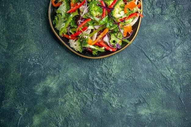 어두운 배경 위에 다양한 신선한 야채와 함께 접시에 맛있는 채식주의 샐러드의 상위 뷰